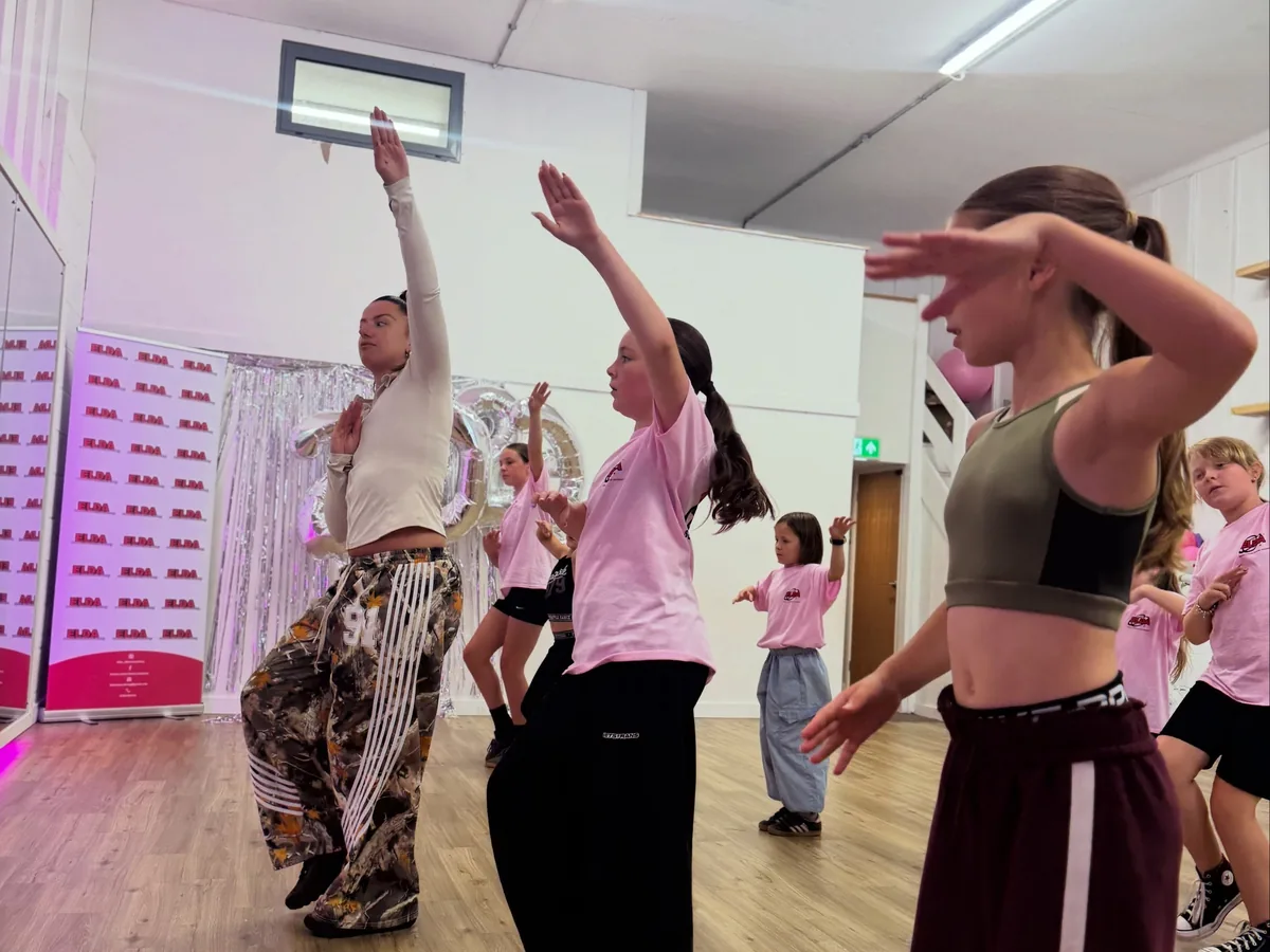 A mixed-ages class with their arms up