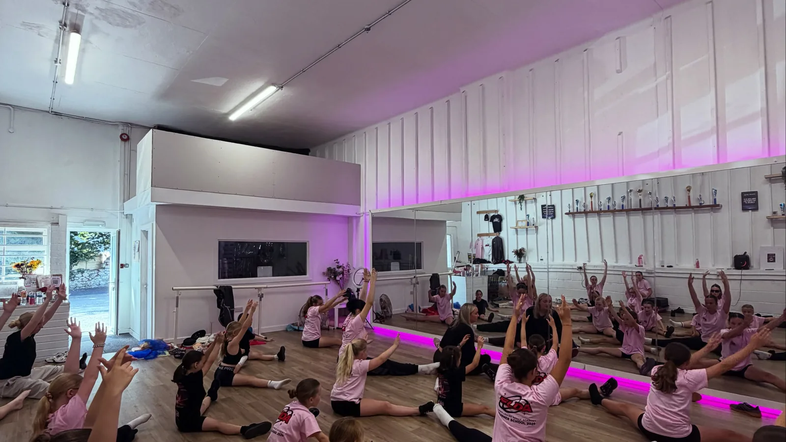 A large class warming up together on the studio floor