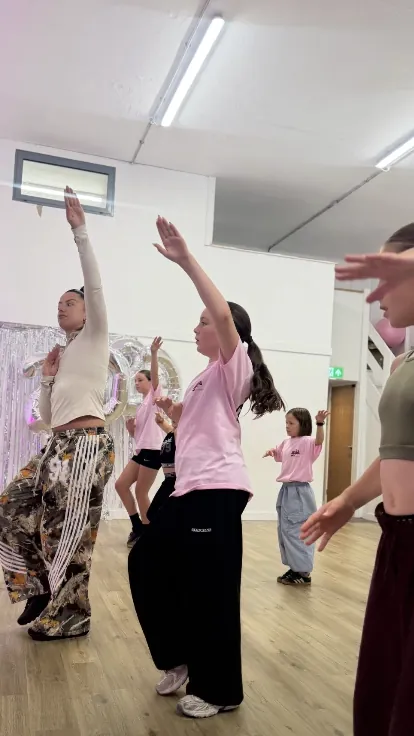 ELDA dancers with arms raised mid-routine in the Camborne studio